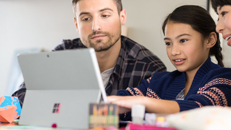 Gezeigt werden drei Personen, die auf ein Tablet sehen