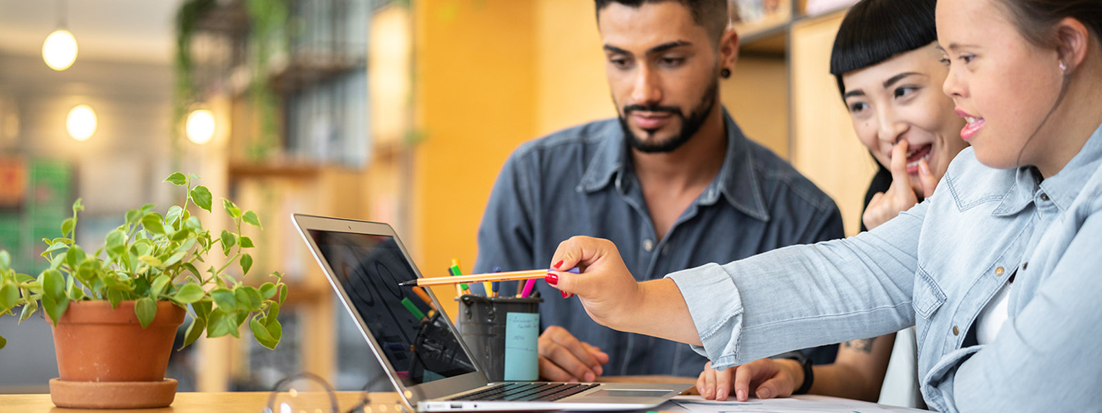 Drei Personen sehen gemeinsam auf einen Laptop in einem hellen Zimmer