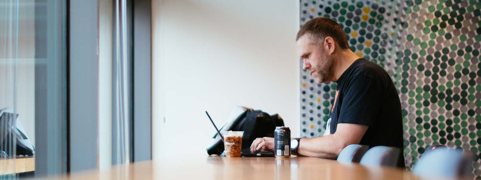 Ein Mann, sitzt vor einem geöffneten Laptop am Tisch.