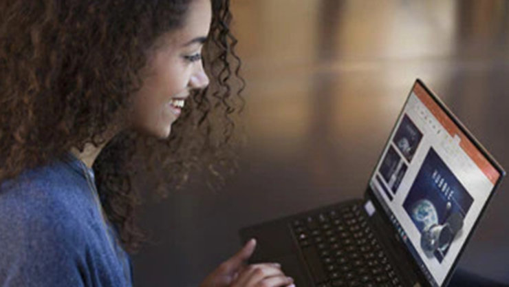 Eine lachende Frau arbeitet an einem Laptop