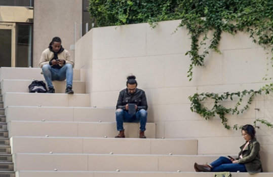 Eine Gruppe von Jugendlichen sitzt auf einer Treppe. Alle haben ein digitales Device in der Hand