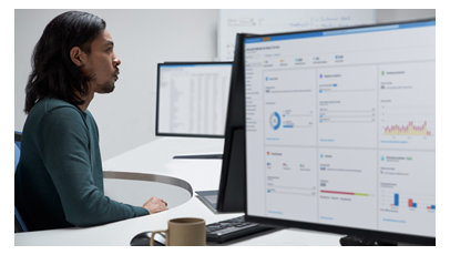 オフィスで複数の画面で作業する男性