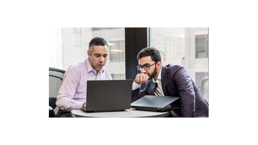 2人の男性の同僚が座ってノートパソコンで何かについて話し合う