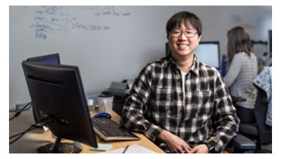 チェック柄のシャツを着た男性が座って微笑んでいる