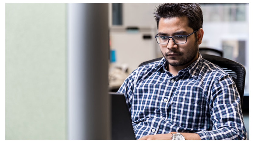 チェック柄のシャツを着た男性開発者がノートパソコンで作業