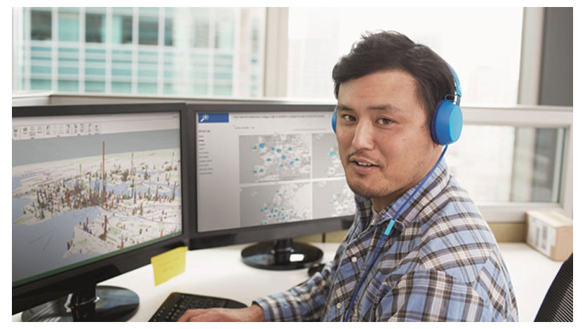 青いヘッドフォンを着けて机に座る男性開発者