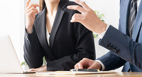 画像：PCを前に会話するビジネスマン