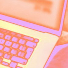 オレンジとピンクのネオンカラーで表現された、ぼやけたノートパソコンのキーボード。