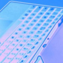 「角度をつけて開かれたノートパソコンのキーボード部分をクローズアップした青みがかった描写」