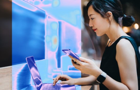 ました。女性がノートパソコンとスマホを使っています。