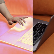 ノートパソコンのトラックパッドに触れる手。