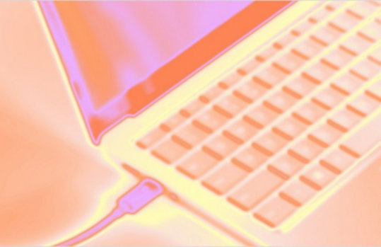 ノートパソコンのキーボードと接続ケーブルの接写に、オレンジ、ピンク、黄色の温かい光の効果が重なっている。