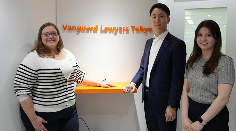 Vanguard Lawyers Tokyoのロゴの前に立つ阿部マリア、木下雅彦、杉本雅史