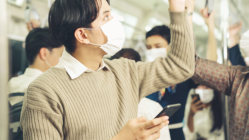 電車内でつり革につかまって上を見上げる人