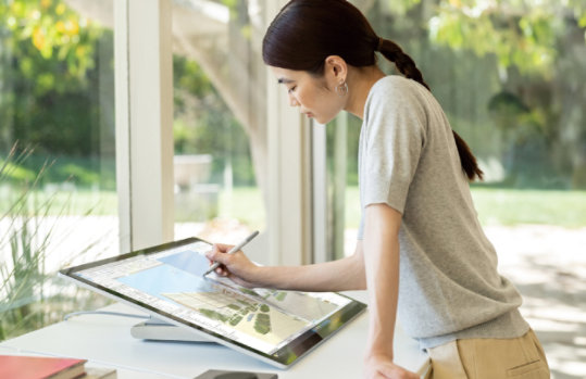 Surface Studio 2+ にペンで書いている女性