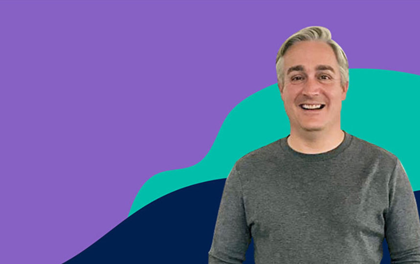 Alistair Stratford is posing with a purple, blue and cyan background behind him