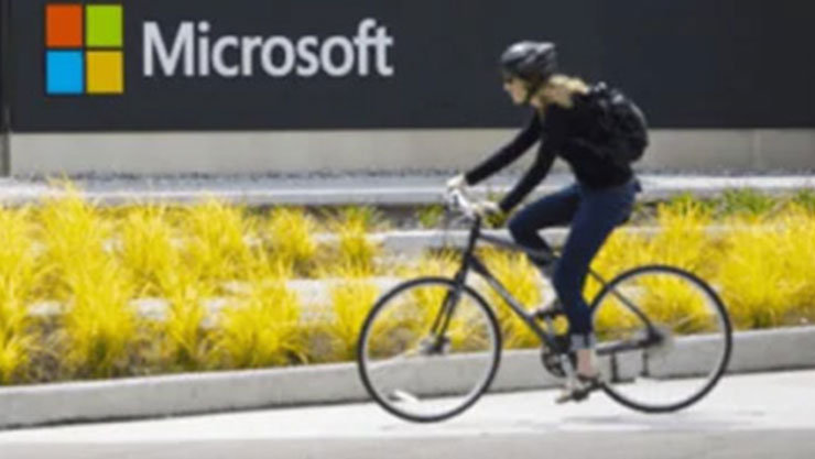 a person riding a bike past a Microsoft sign