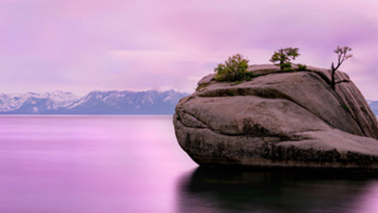 a large rock emerging from a lake 