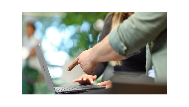 A man pointing to the Microsoft Devices Sustainability Report on a Microsoft laptop
