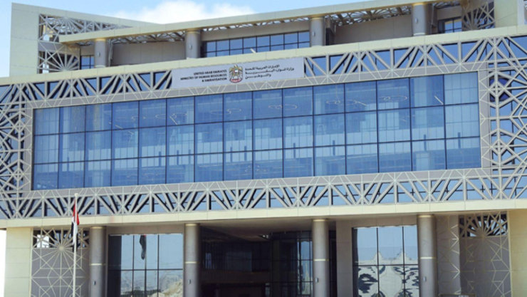 Person sitting at a desk looking at papers and a laptop