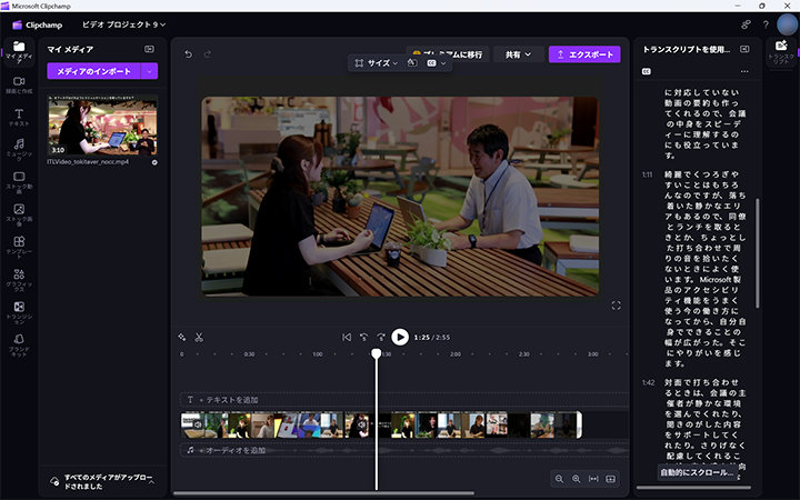 Microsoft Clipchampのスクリーンショットには、テーブルでラップトップを使っている二人の会話を示す動画と、右パネルに表示された文字起こしが映っています。