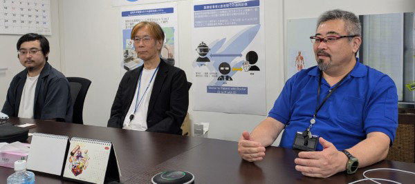 会議室のテーブルに着席する3人の男性。