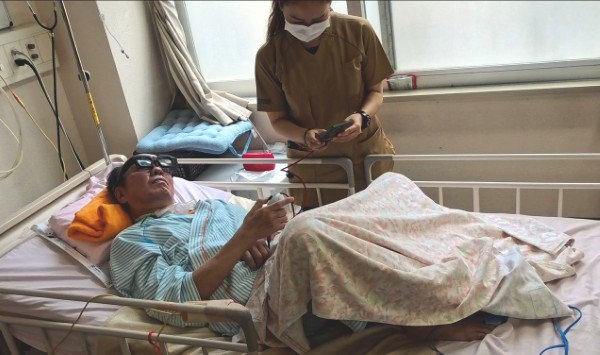 ベッドに横たわりスマートグラスを装着した患者と、傍らで端末を操作する医療スタッフ。