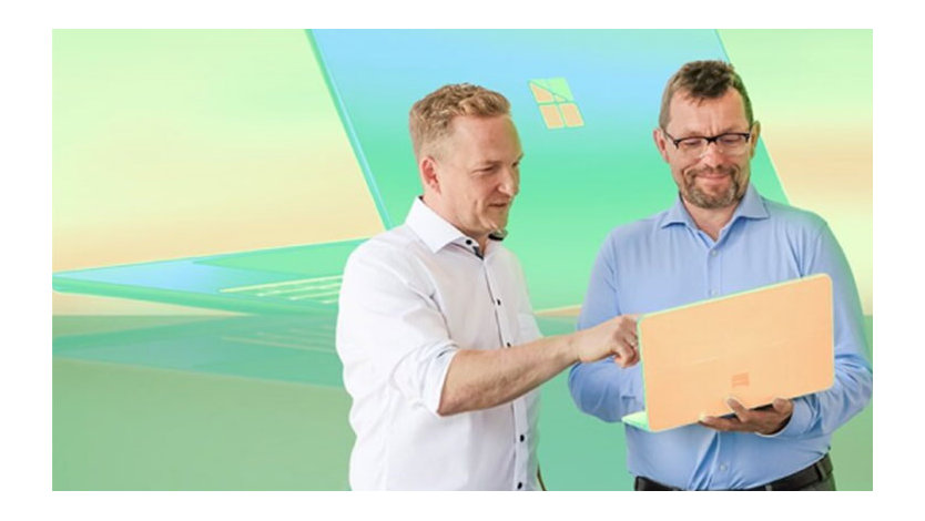 Zwei Männer interagieren mit einem Laptop vor stilisiertem Hintergrund mit Windows-Logo.