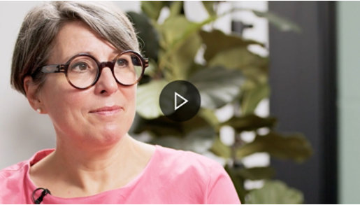 EIne Frau mit Brille und rosa Oberteil blickt nach rechts.