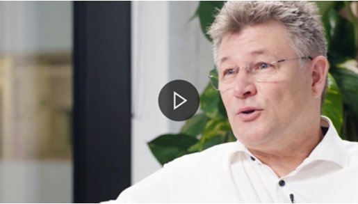 Ein Mann mit Brille und weißem Hemd blickt nach links.