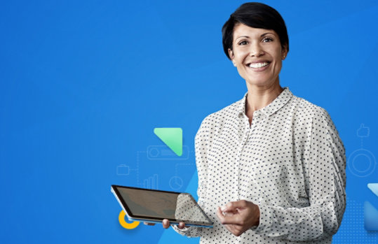 Eine Frau mit kurzen schwarzen Haaren trägt ein gepunktetes weißes Hemd und hält ein Tablet lächelnd in der Hand.