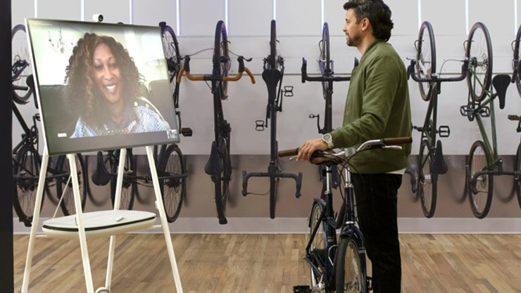 Das Bild zeigt ein Teams-Telefonat über ein Microsoft Surface Hub, welches sich in einem Fahrradgeschäft befindet.