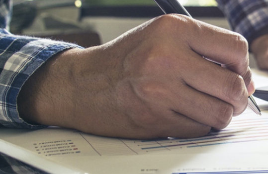 Eine Person schreibt etwas auf ein Blatt Papier.