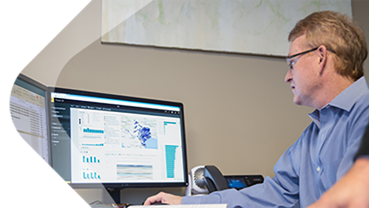 Ein Mann mit Brille sitzt vor zwei Bildschirmen.