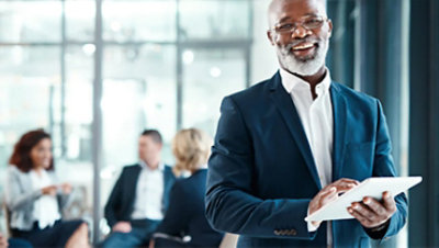 Ein Mann lächelt in die Kamera, er trägt einen blauen Anzug