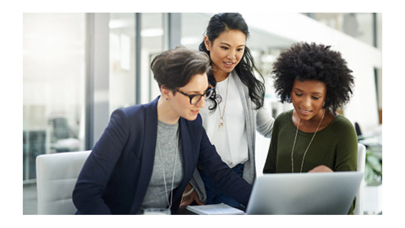 Drei Frauen schauen gemeinsam auf einen Laptop