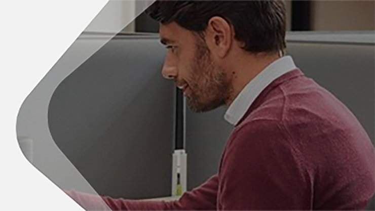 Männliche Person sitzt in einem Büro und arbeitet auf einem Touchscreen.