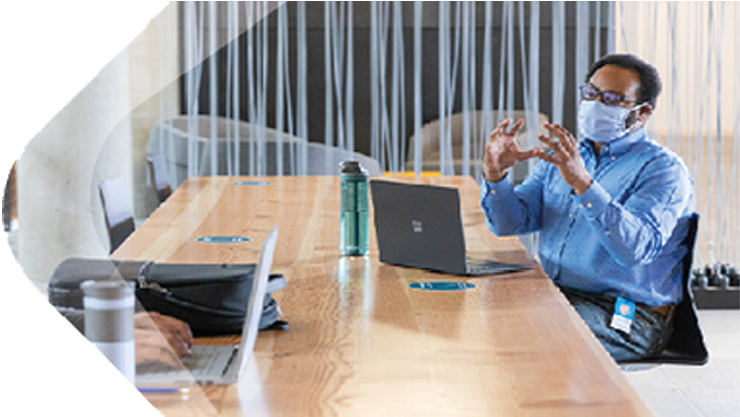 Ein Mann mit Schutzmaske sitzt in einem Meetingraum