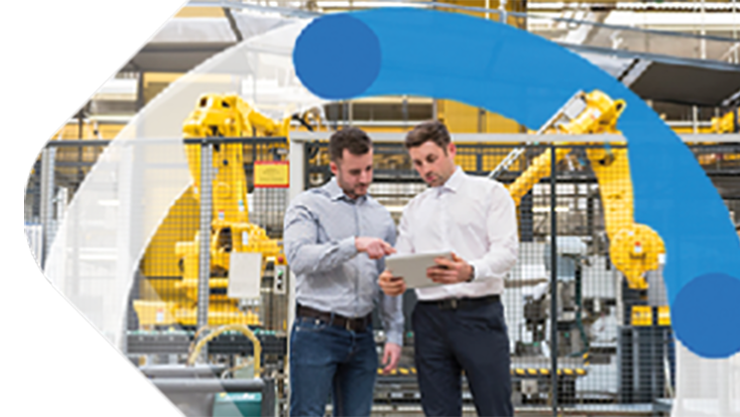 Zwei Mitarbeiter, die in einer Produktionshalle stehen und gemeinsam in ein Tablet schauen