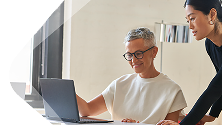 Zwei weibliche Personen schauen gemeinsam auf einen Laptop.