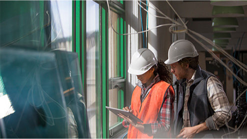 Zwei Personen mit Schutzhelmen in einer Fabrikanlage