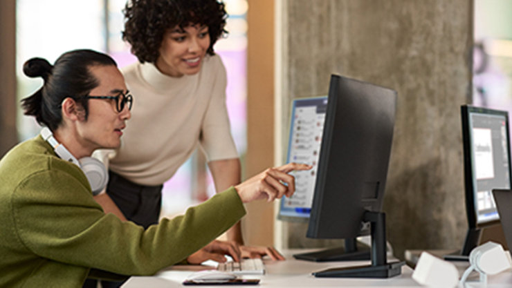 Zwei Personen arbeiten an Computern in einem Büro.
