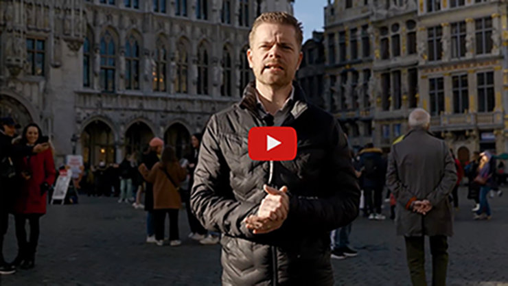 person talking on Grand Place in Belgium overlay of icon of youtube