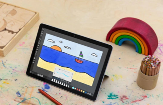 Ein Tablet steht auf einem Kinderschreibtisch. Auf dem Bildschirm des Tablets ist ein gemaltes Bild zu sehen.