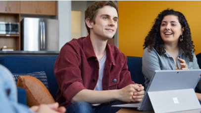 Dieses Bild zeigt zwei sitzende, sich unterhaltende Schüler vor einem Surface Gerät.