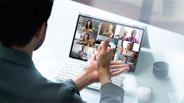 男性がパソコン上のメンバーと手話で会議をしている様子