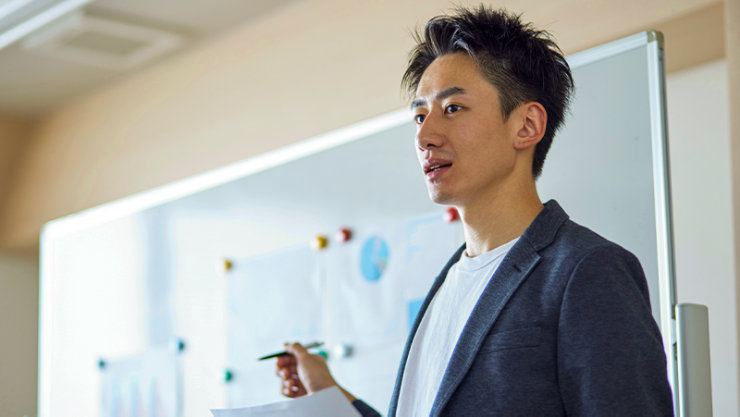 ホワイトボードの前で話をする教師