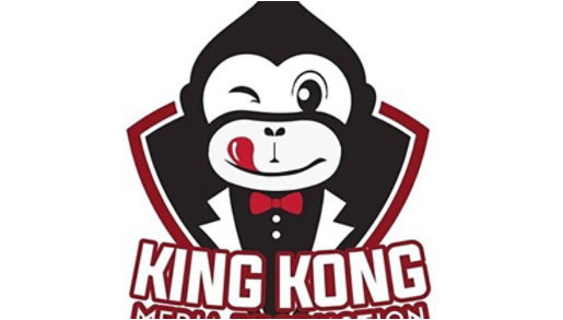King Kong Media Production λογότυπο στη μέση σχέδιο γορίλα μαύρος με λευκό πρόσωπο και τη γλώσσα κόκκινη έξω, μέσα σε ρόμβο, κεφαλαία λευκά με κόκκινο περίγραμμα γράμματα