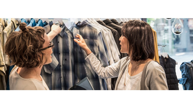 Two women checking out the clothes in a clothing store