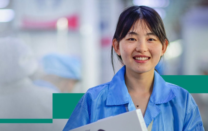 A woman smiling with her colleagues working in the background